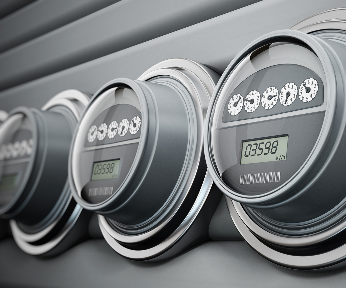 Four digital utility meters mounted on a gray wall, displaying numerical readings. Each meter has a circular design with a digital screen showing the numbers clearly