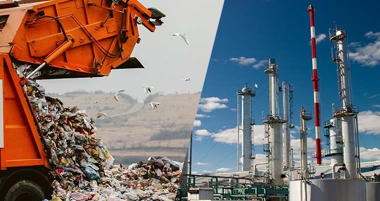 A large orange garbage truck is dumping a pile of waste onto a landfill, with seagulls flying nearby. On the right, a series of industrial smokestacks and processing towers are visible against a blue sky with scattered clouds, indicating a facility related to energy or manufacturing