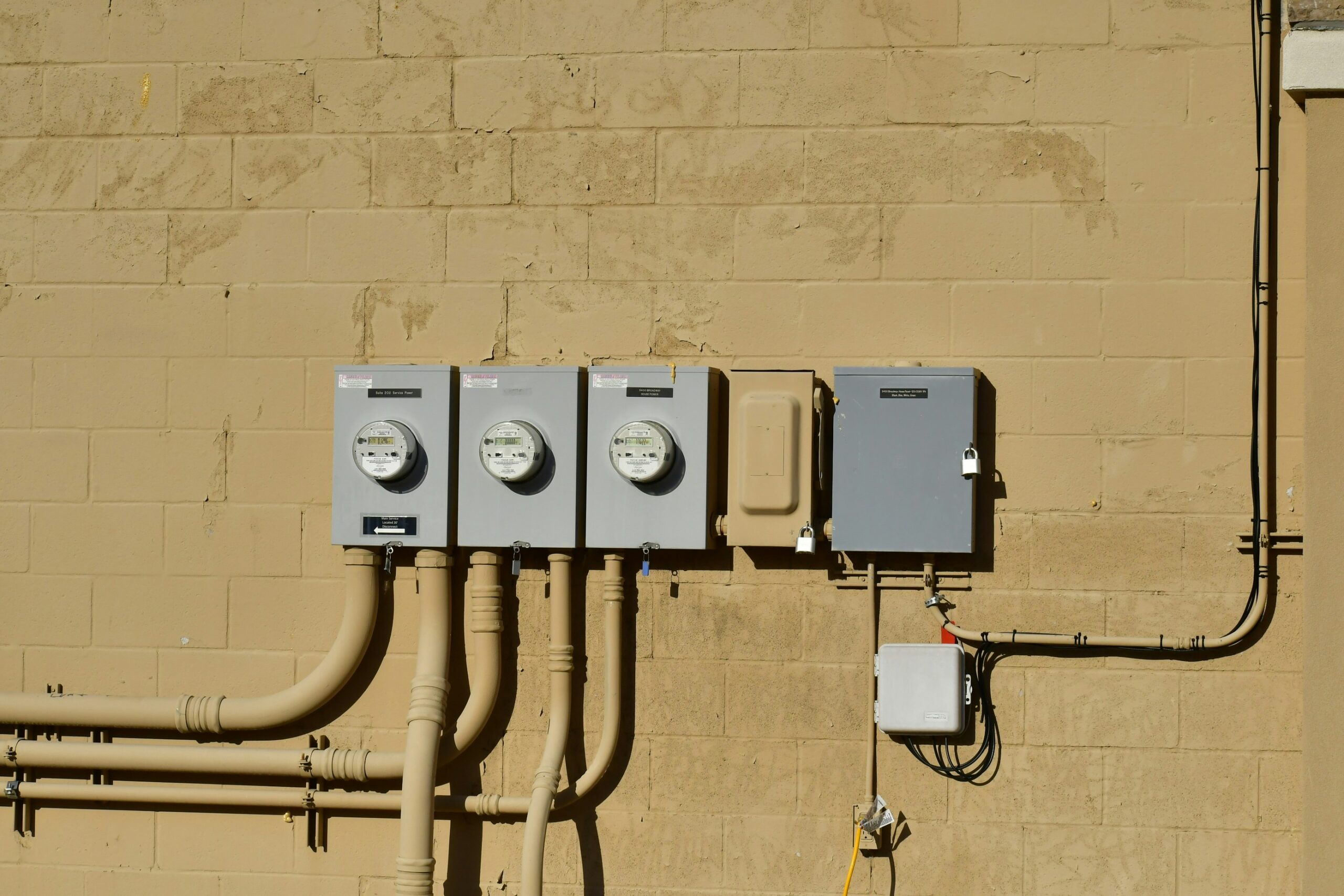 Three utility meters mounted on a beige wall. A smaller gray box is positioned beside the meters.