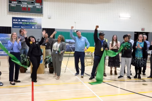 A group of people celebrates the opening of a solar power initiative at the MLK Jr. Middle School gym.